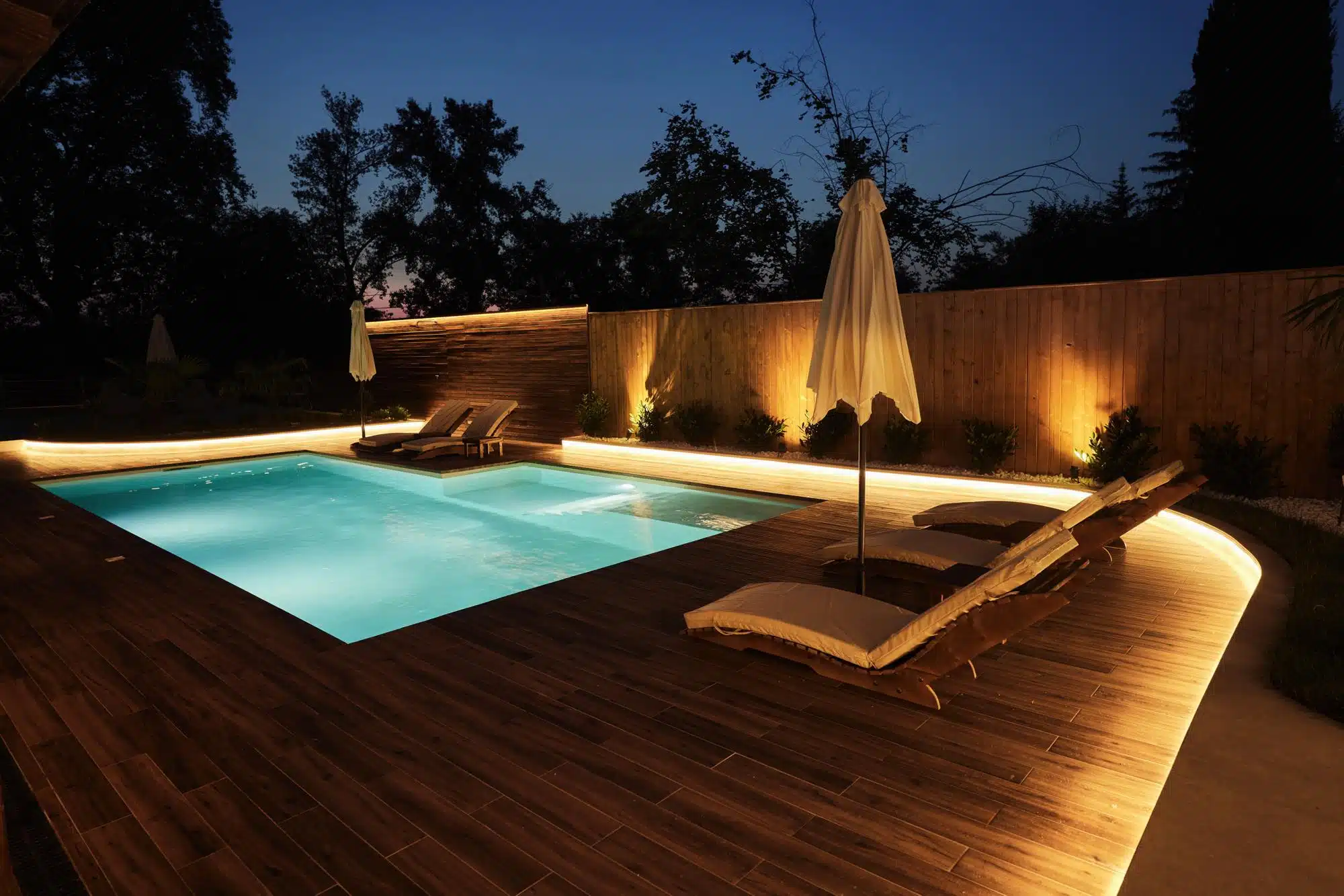 Custom deck and patio lighting around a swimming pool and seating area by Landscape Lighting Resources in Charlotte NC