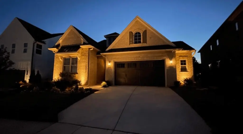 Front of home lighting illuminating the garage and brick facade by Landscape Lighting Resources in Charlotte NC